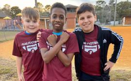 three boys posing with matching dark red shirts with Flag Football in white writing 