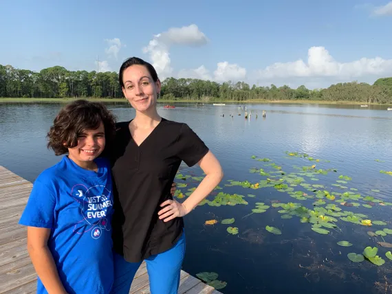 Camper and his mother pose in front of lake at camp muskogee