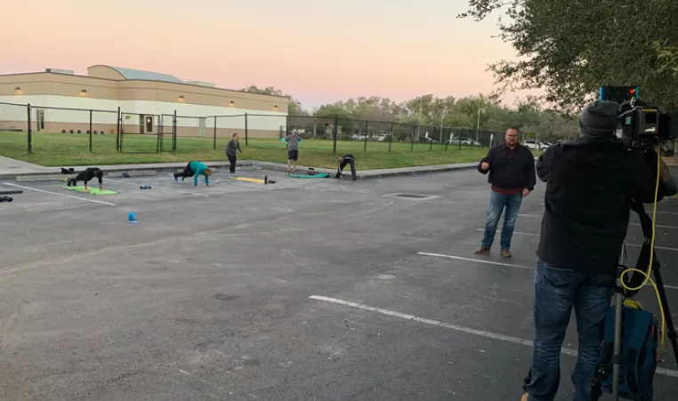 people working out at Greater Palm Harbor Y parking lot during news crew filming